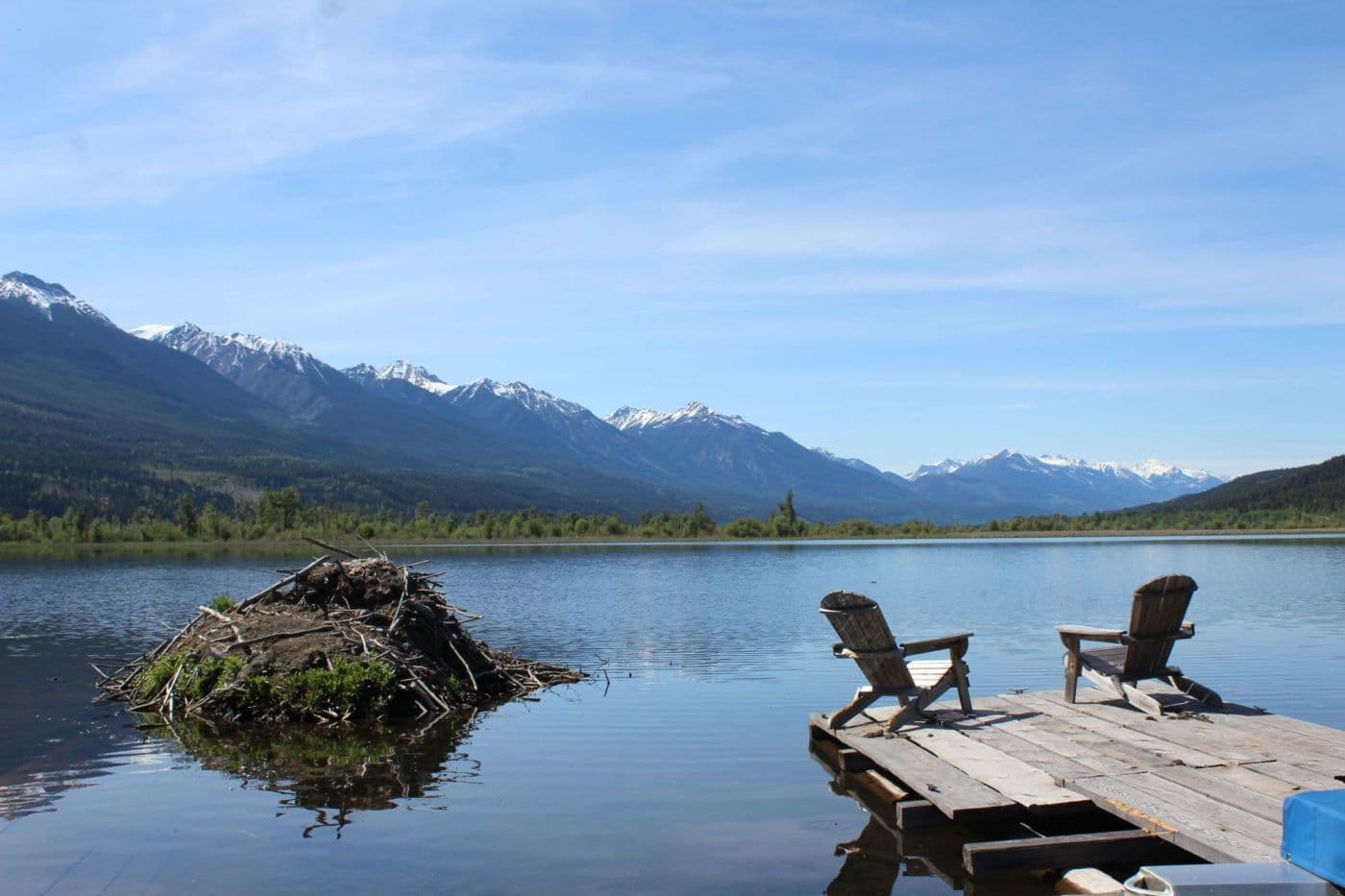 Two chairs on a dock overlooking a calm mountain lake